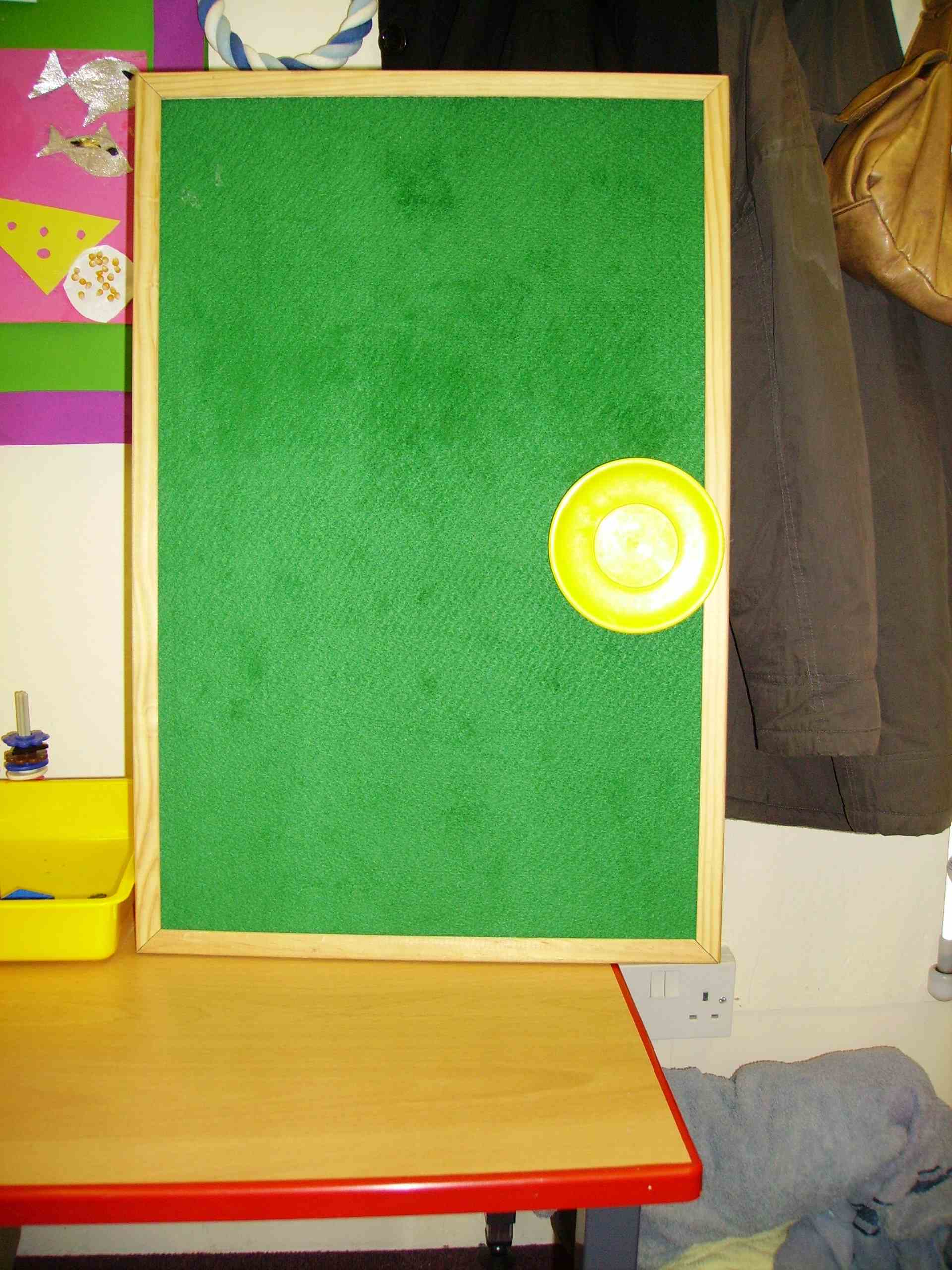 Sarah's timetable board. It now displays the objects representing the second and third of the first three activities taking place one school morning. From left to right they are a dish and a small plastic plate.